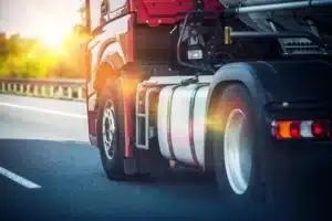 Side view of red truck driving down road